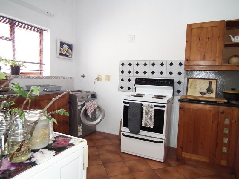 A functional kitchen featuring wooden cabinetry, tiled flooring, a tiled backsplash, and a freestanding stove, offering a traditional aesthetic with potential for modernization.