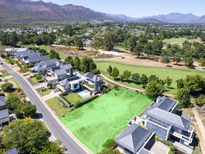 Aerial view of a prime vacant residential plot situated adjacent to a golf course in a well-established estate.