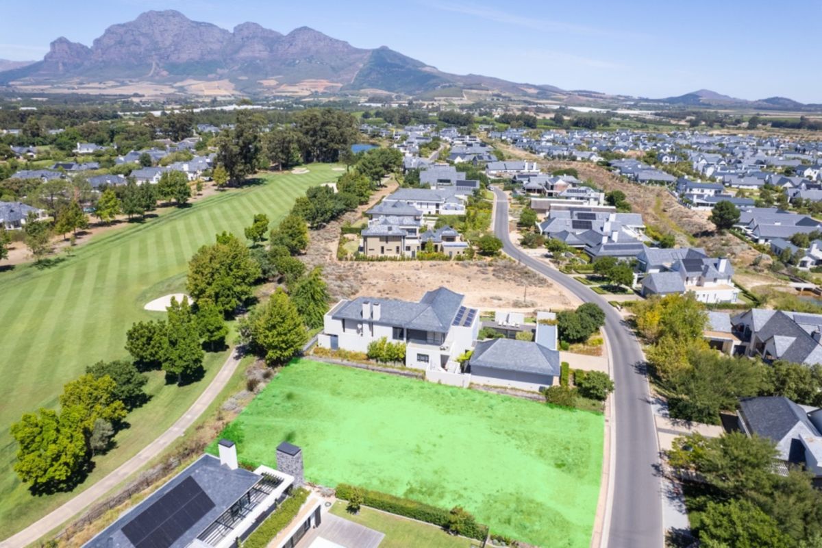 Aerial view of a vacant residential plot situated in a golf estate, featuring scenic mountain views and direct access to the golf course.
