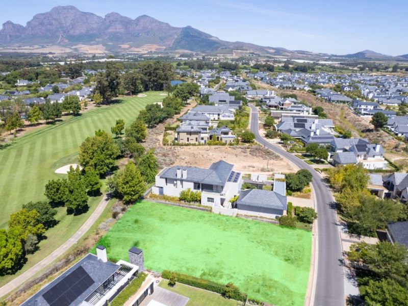 Aerial view of a vacant residential plot situated in a golf estate, featuring scenic mountain views and direct access to the golf course.