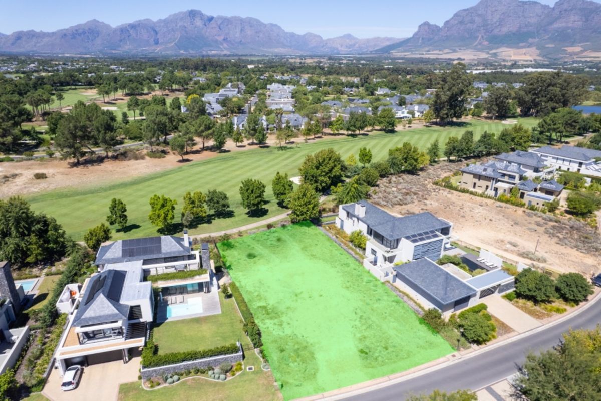 Aerial view of a prime vacant residential plot situated in a prestigious estate, featuring direct golf course frontage and scenic mountain views.