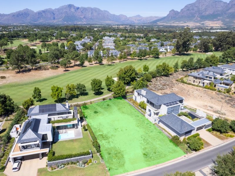 Aerial view of a prime vacant residential plot situated in a prestigious estate, featuring direct golf course frontage and scenic mountain views.