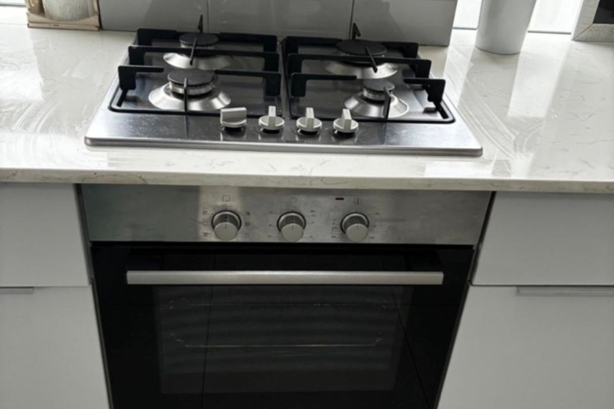 A clean kitchen area featuring a built-in Bosch oven, gas hob, stone countertop, and a modern subway tile backsplash.