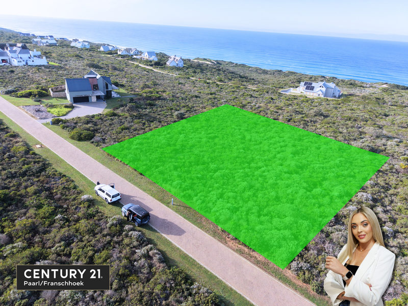 Aerial view of a vacant residential plot situated in a coastal estate, featuring paved road access and proximity to the ocean.