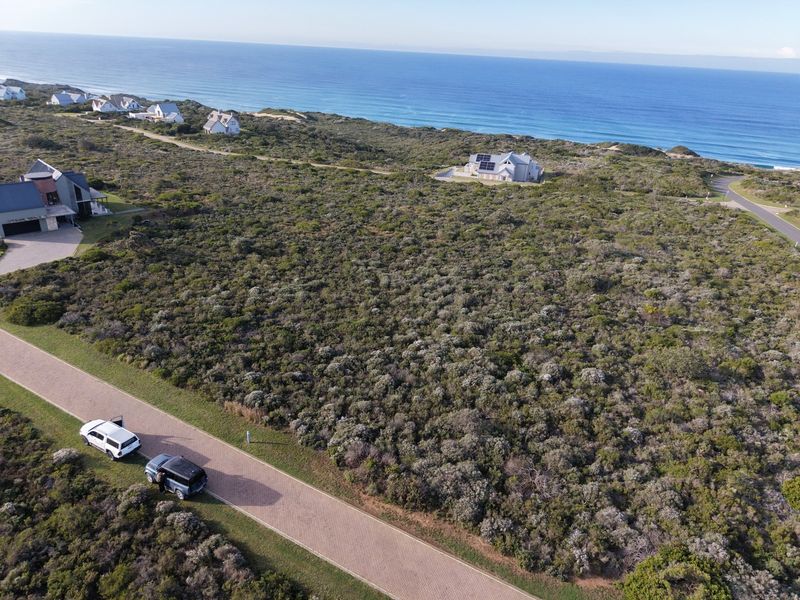 Aerial view of a vacant residential plot situated in a coastal estate, featuring native vegetation and proximity to the ocean.