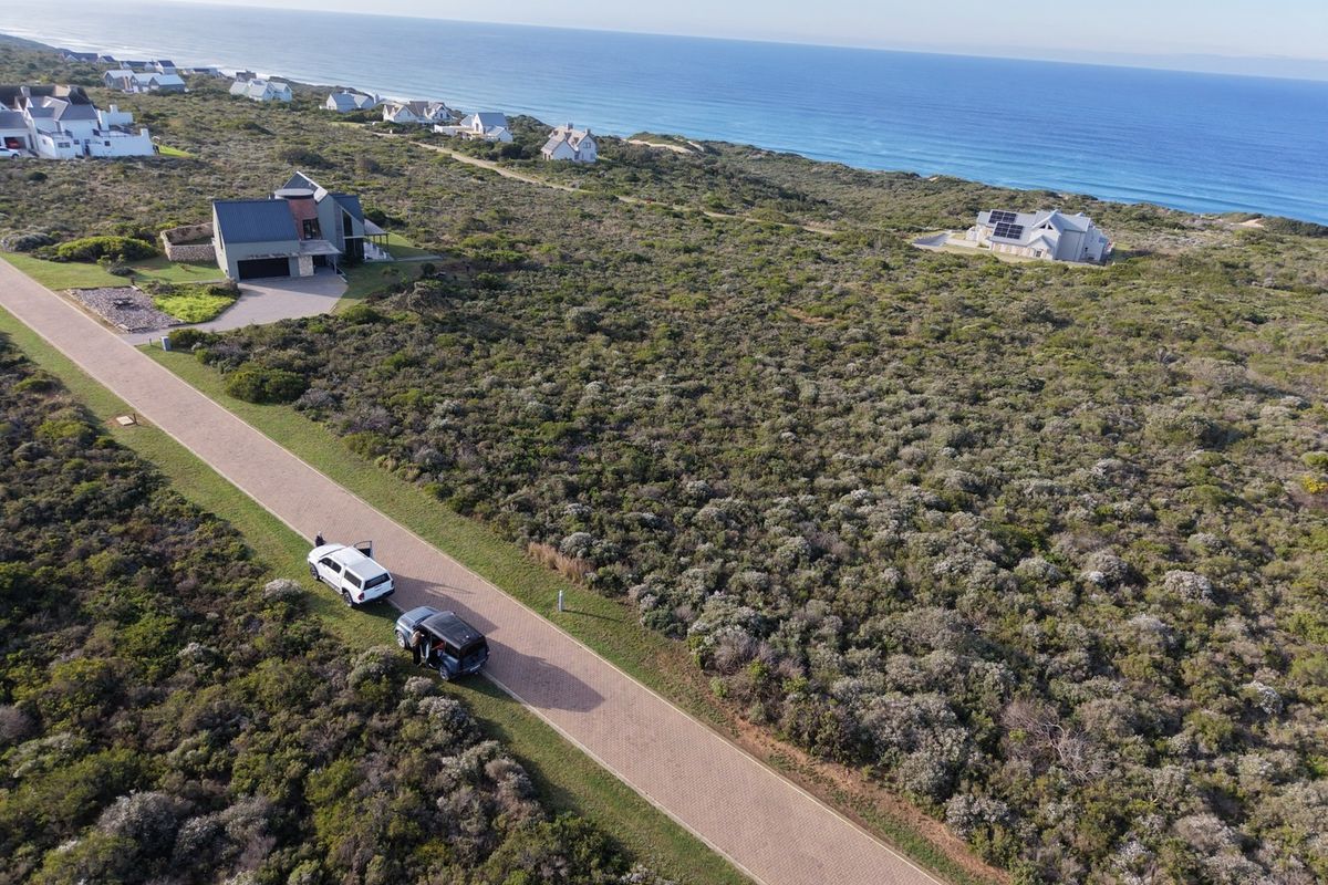 Aerial view of a coastal residential development featuring paved roads and surrounding natural vegetation with ocean views.