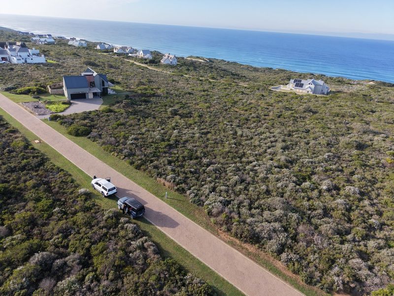 Aerial view of a coastal residential development featuring paved roads and surrounding natural vegetation with ocean views.