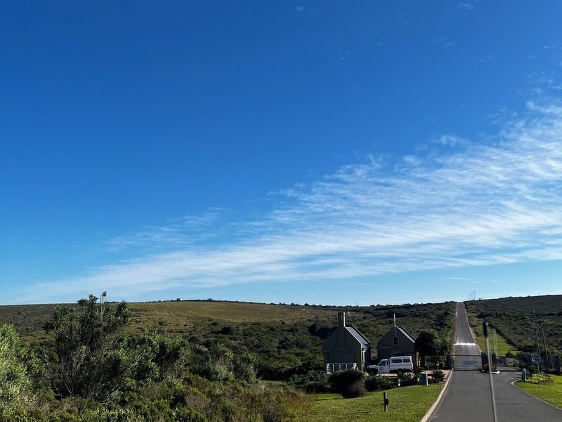 A view of the paved access road leading through the natural landscape towards the property entrance.