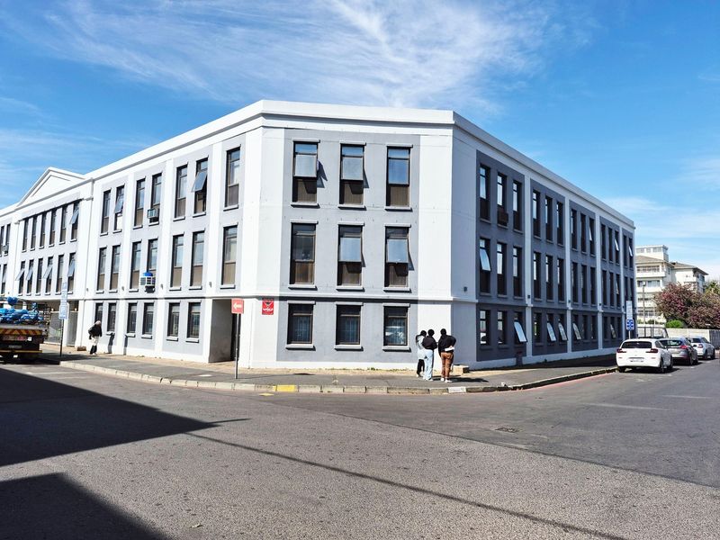 A multi-story apartment building exterior featuring a corner facade with numerous casement windows and a clean, modern architectural finish.