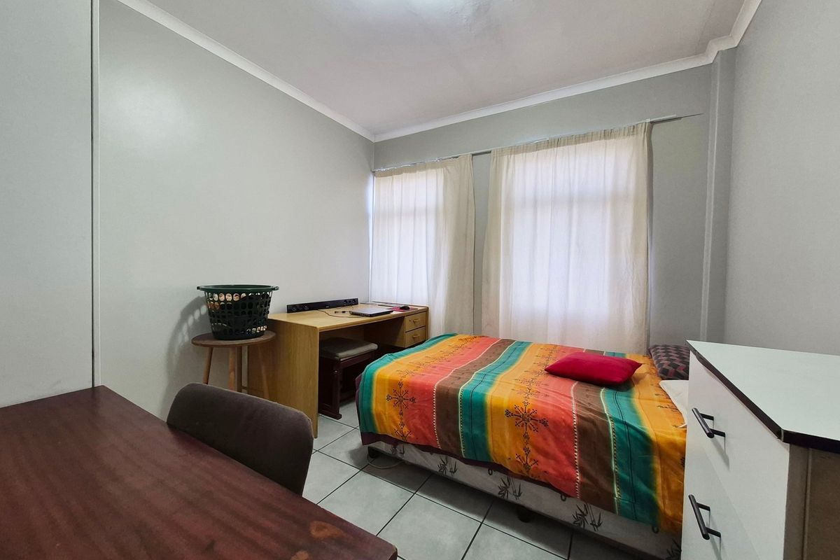 A functional bedroom featuring tiled flooring and neutral wall finishes, providing a practical space with natural light from the window.