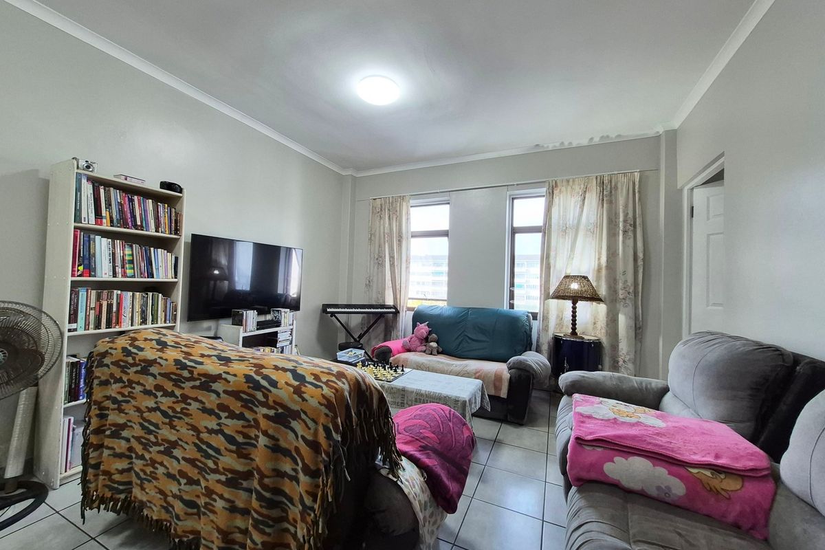 A functional living room featuring tiled flooring, dual windows for natural light, and coved ceiling detailing.