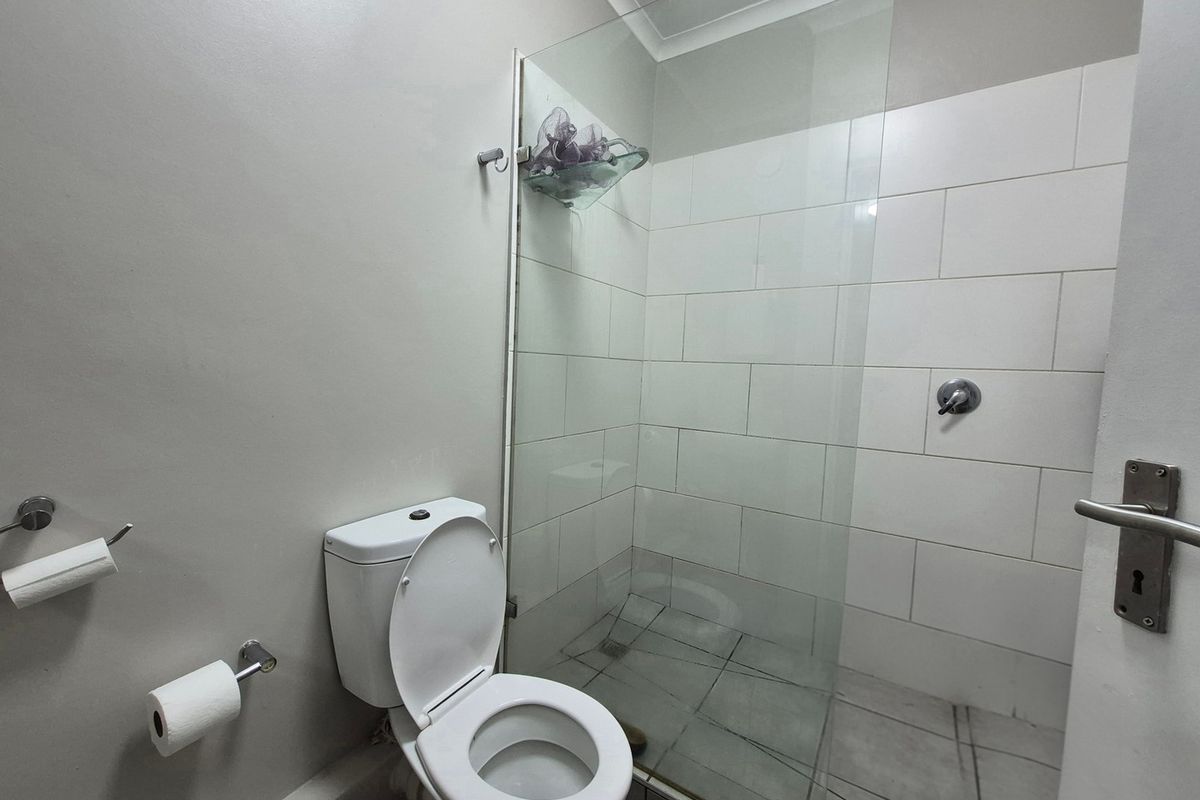 A clean, functional bathroom featuring a glass-enclosed shower, tiled walls, and standard toilet fixtures.