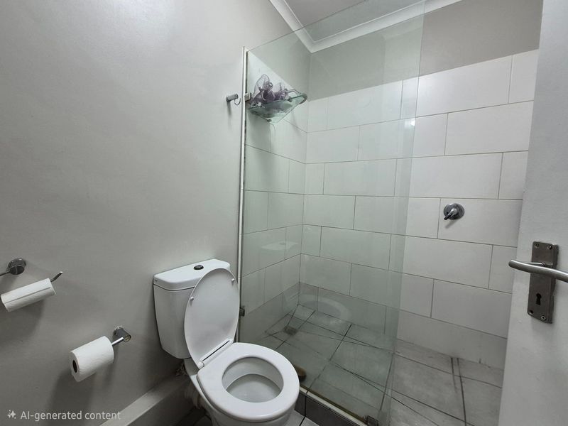 A clean, functional bathroom featuring a glass-enclosed shower, tiled walls, and standard toilet fixtures.