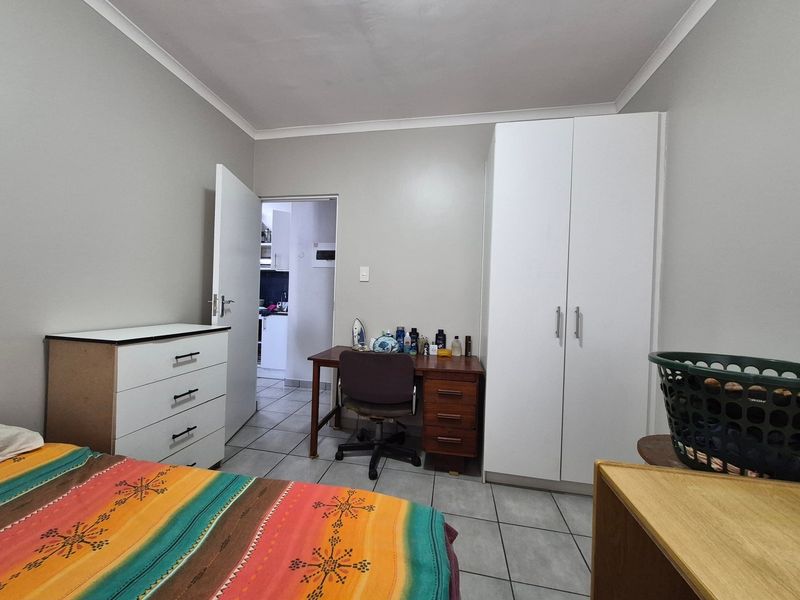 A bedroom featuring tiled flooring, a built-in wardrobe, and access to an adjacent room.
