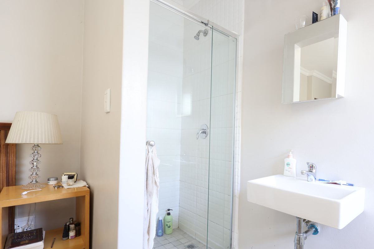 A functional bathroom featuring a glass-enclosed shower with tiled flooring and a modern wall-mounted basin with chrome fixtures.