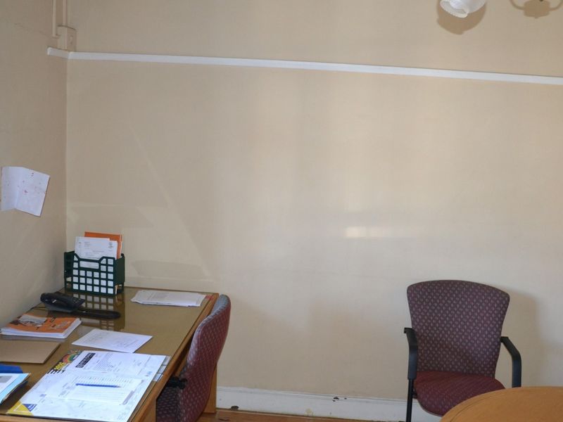 A functional office space featuring neutral wall finishes and natural light from a side window.