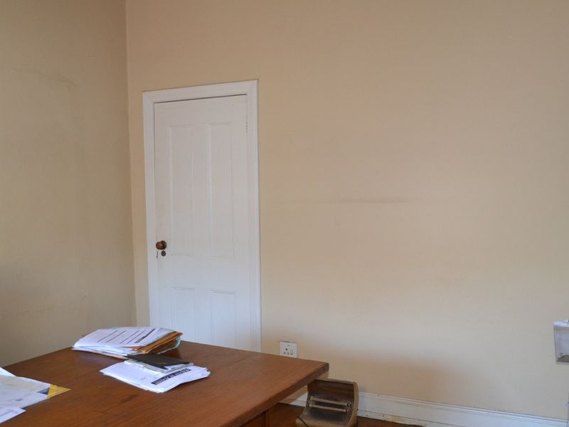 A functional office space featuring neutral wall tones, traditional door hardware, and standard electrical infrastructure.