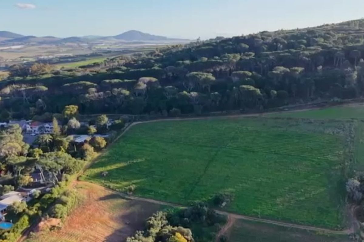 An aerial view of a large plot of land surrounded by trees and natural landscape.