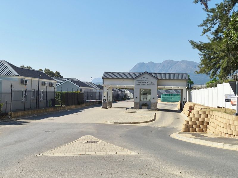 The main entrance and security gatehouse of Bergendal Country Villas, featuring paved access, electric fencing, and mountain views.