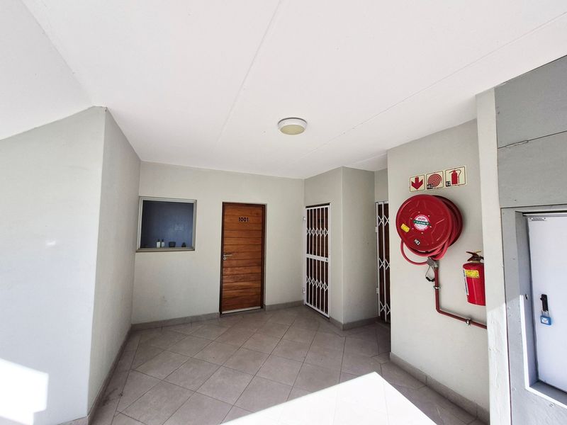 A clean and well-maintained apartment entrance lobby featuring tiled flooring, a secure timber door, and essential fire safety equipment.