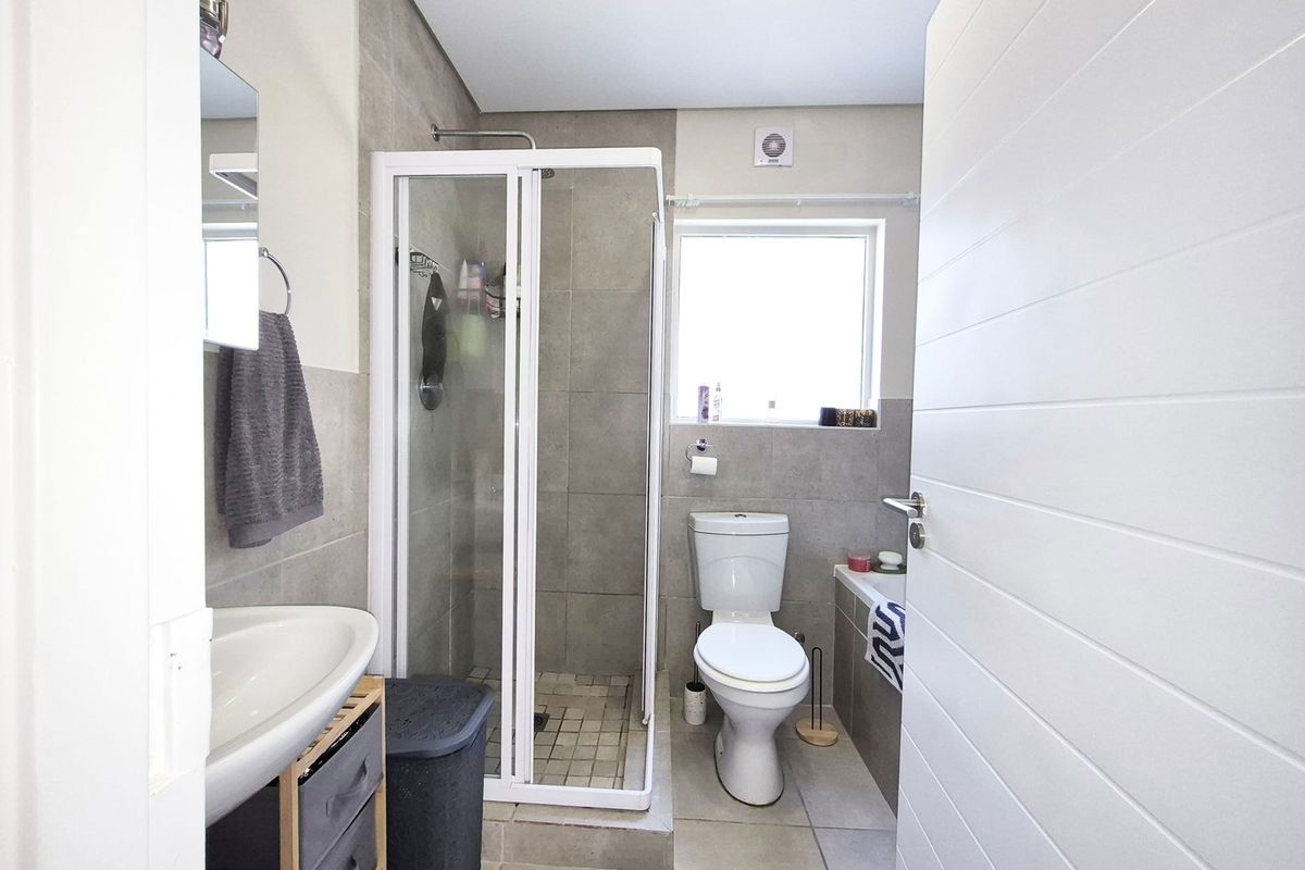 A functional bathroom featuring a shower enclosure, bathtub, toilet, and washbasin with neutral wall and floor tiling.