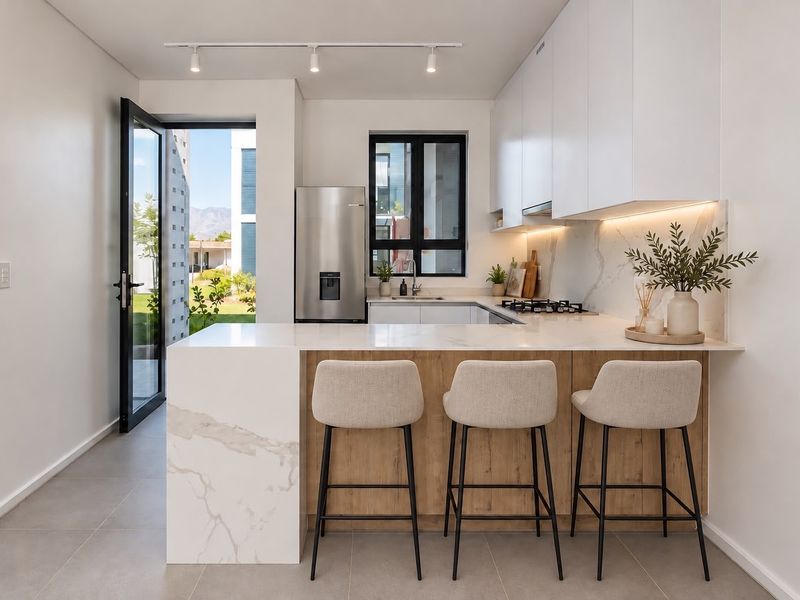 Modern kitchen featuring marble-look stone countertops, a breakfast bar, built-in cabinetry, gas hob, and direct access to an outdoor area.