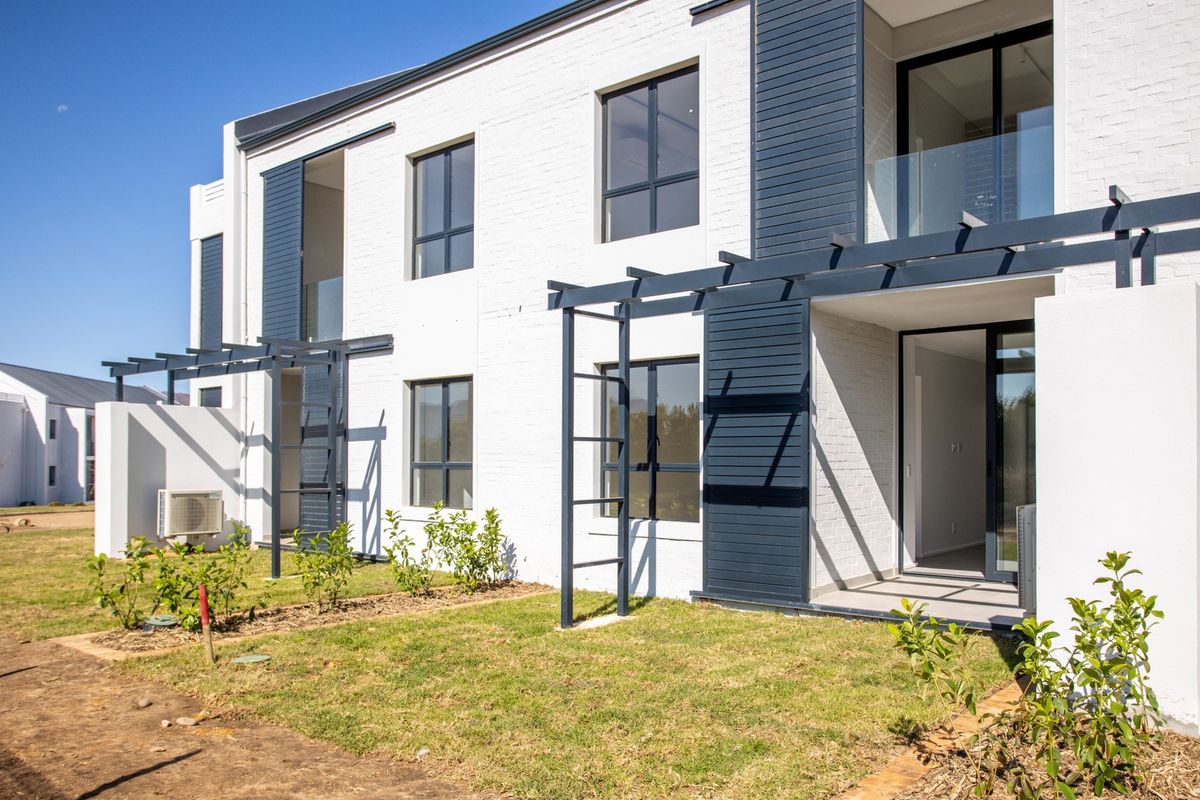 Modern apartment exterior featuring a white brick facade, dark timber pergolas, glass balustrades, and private ground-floor patio access.