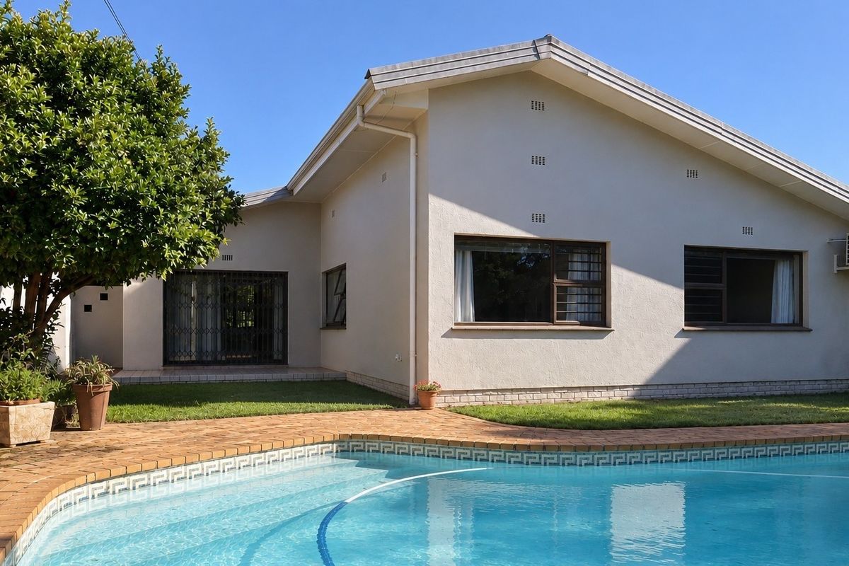 Rear view of the house featuring a swimming pool, brick paved surround, and well-maintained exterior walls with security gates.