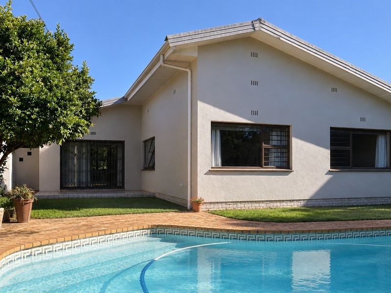 Rear view of the house featuring a swimming pool, brick paved surround, and well-maintained exterior walls with security gates.
