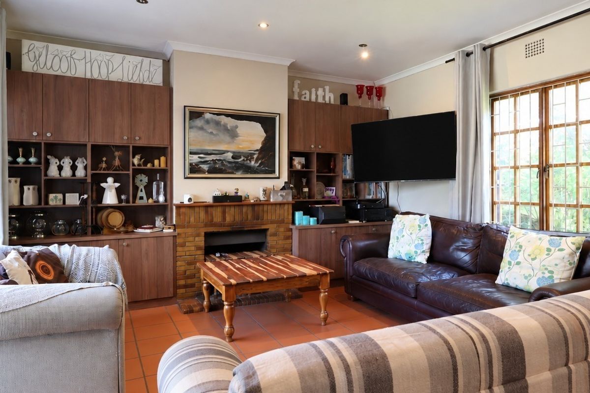 A comfortable living room featuring a brick fireplace, extensive built-in cabinetry, and tiled flooring, offering a functional and well-lit space for relaxation.