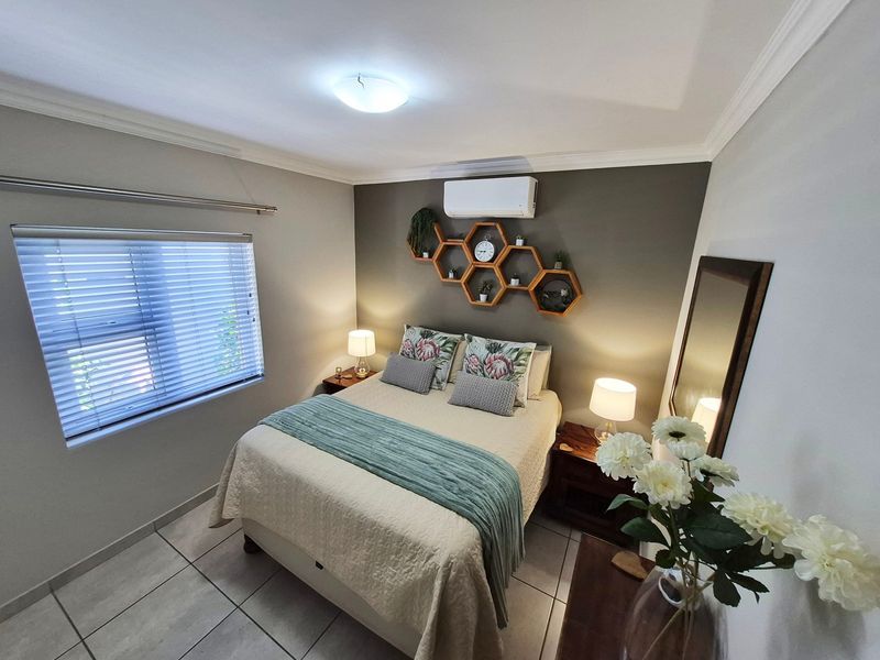 A well-maintained bedroom featuring tiled flooring, an air conditioning unit, and venetian blinds, offering a comfortable and functional living space.