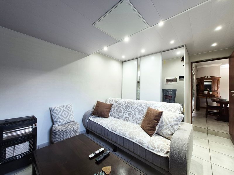 A living area featuring tiled flooring, recessed ceiling lighting, and a built-in sliding door wardrobe, providing functional storage space.
