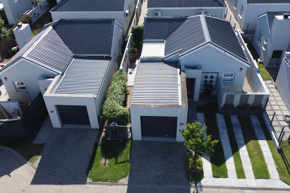 Aerial view of a modern townhouse complex featuring corrugated metal roofing, paved driveways, and private garage access.