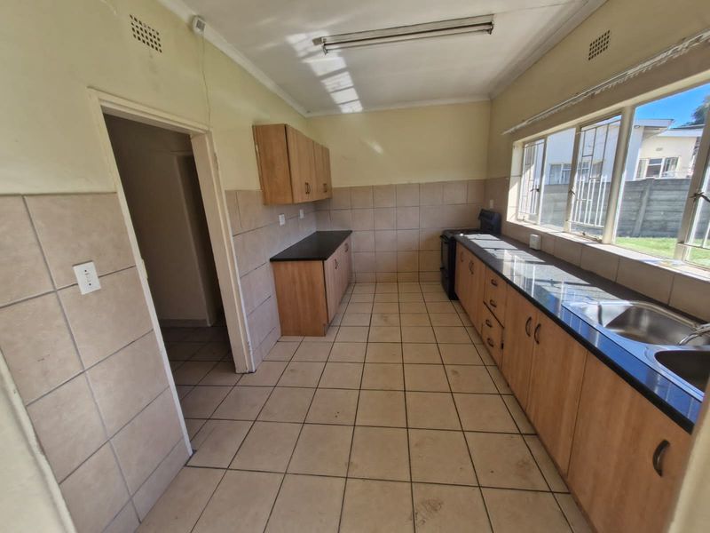 A functional kitchen featuring built-in cabinetry, laminate countertops, a double sink, and tiled flooring. The space is ready for a modern update.