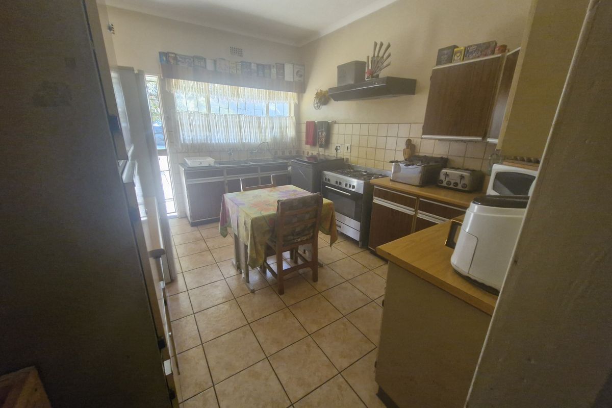 A functional kitchen featuring tiled flooring, built-in cabinetry, a double sink, and a gas stove with an extractor fan.