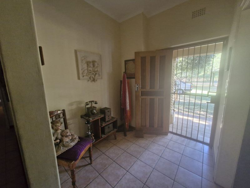 Entrance foyer featuring tiled flooring, a solid wooden front door, and a security gate providing access to the exterior.
