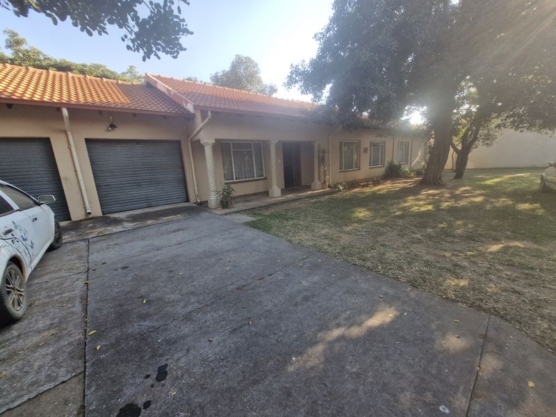 Front elevation of a single-story house featuring a concrete driveway, double garage with roller doors, and a covered porch with decorative columns.
