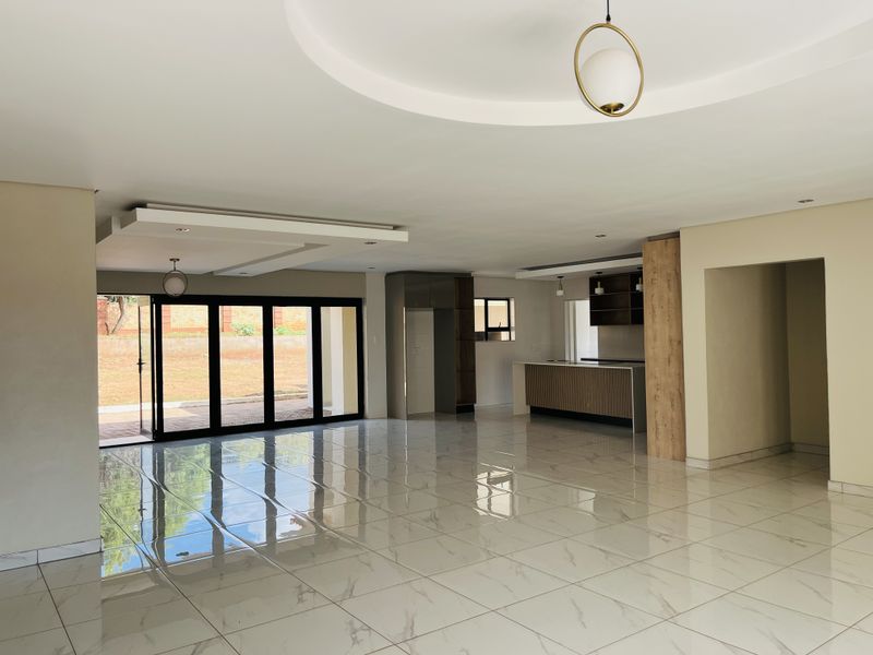 Spacious open-plan living and kitchen area featuring modern porcelain tiles, recessed ceiling details, and large bi-fold doors leading to the outdoor space.