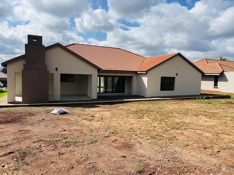 Rear view of a modern house featuring a covered patio with an external fireplace, sliding glass doors, and a tiled roof.