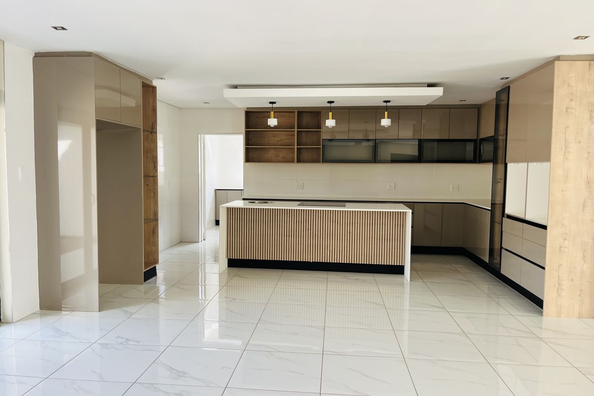 Modern, spacious kitchen featuring a central island, sleek built-in cabinetry, and high-quality tiled flooring in a bright, open-plan layout.
