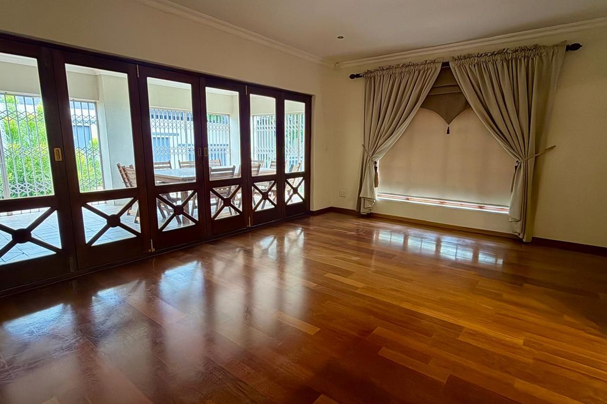 Spacious living area featuring polished hardwood flooring and large wooden folding doors that open onto a covered patio.