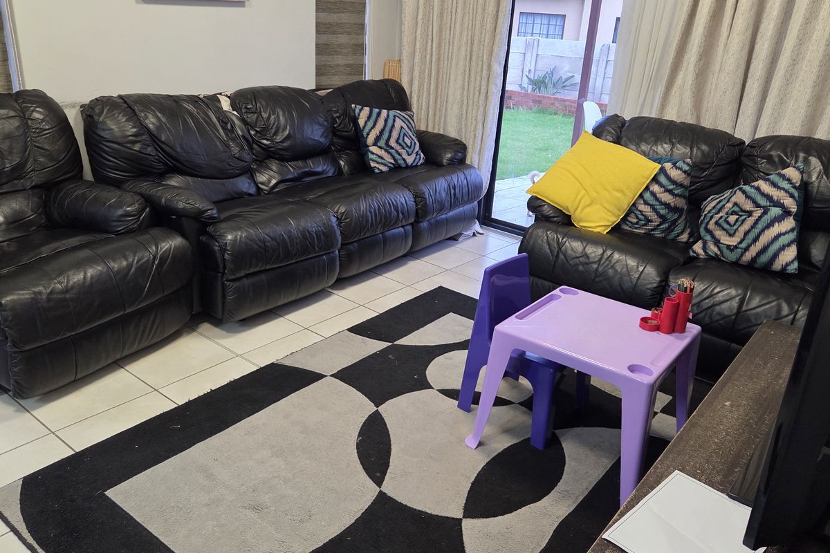 A living room featuring tiled flooring and sliding glass doors that provide direct access to the rear garden area.