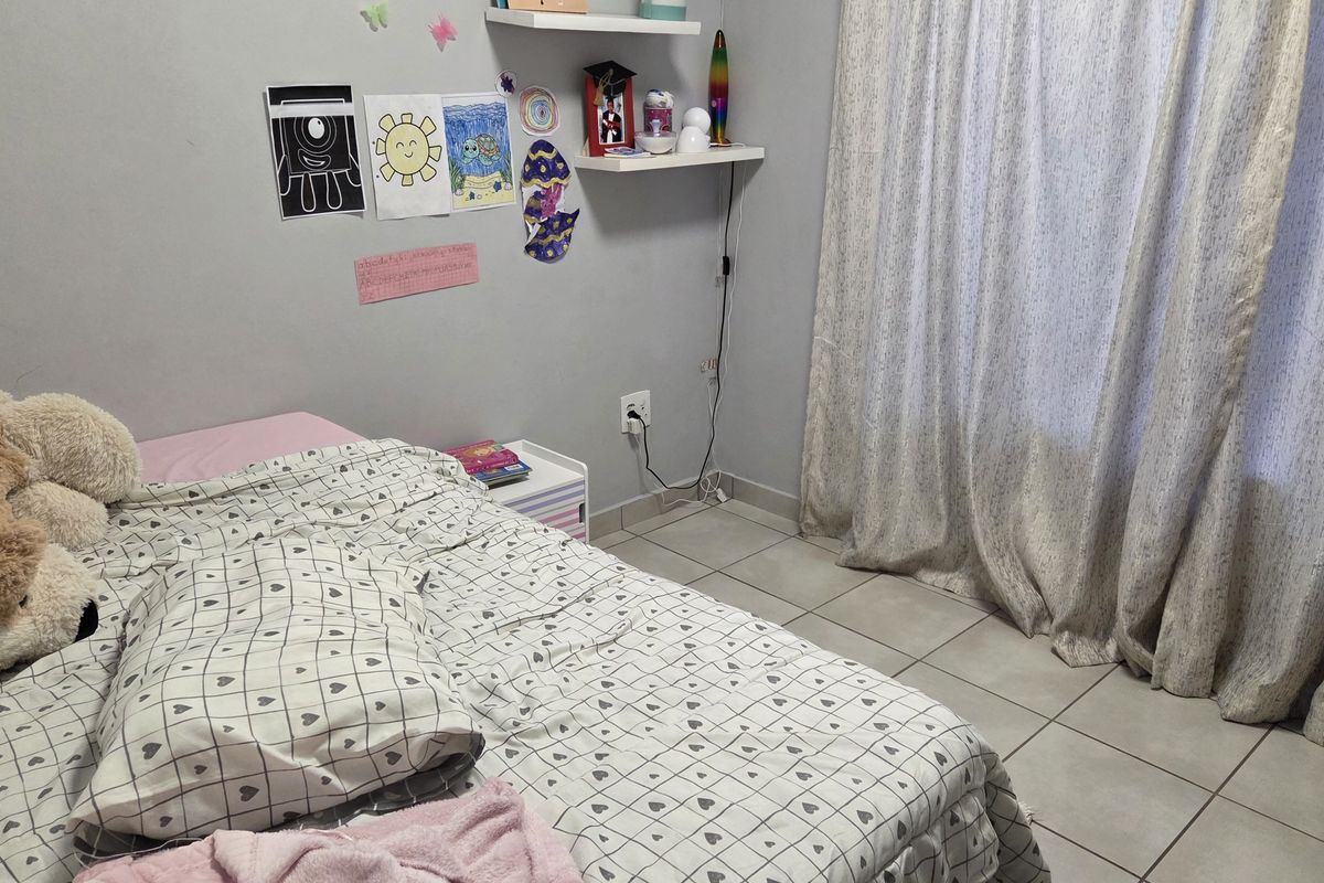 A bedroom featuring tiled flooring and a window with curtains.