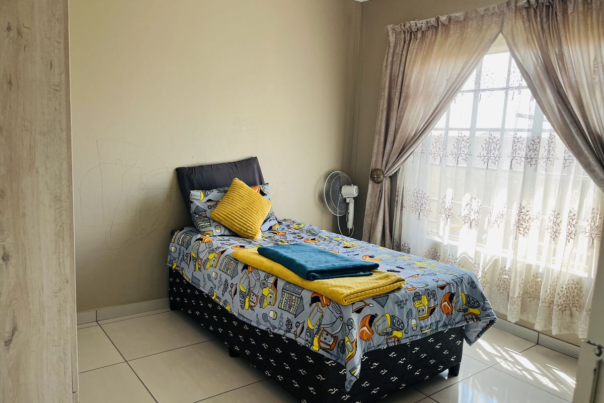 A bedroom featuring tiled flooring, a large window with curtains, and built-in cabinetry.