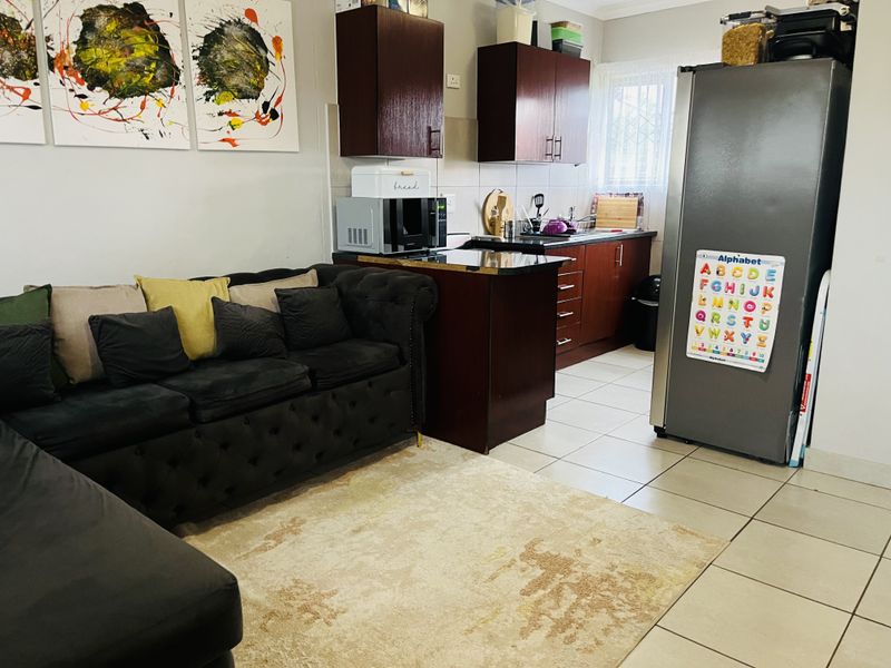 Open plan living area featuring a compact kitchen with dark wood cabinetry, granite countertops, and tiled flooring throughout.