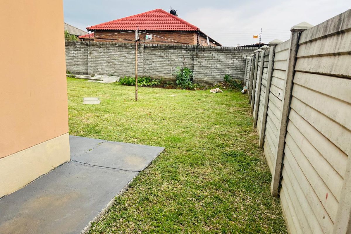 A private rear garden featuring a lawn, concrete paving, and secure precast concrete boundary walling.