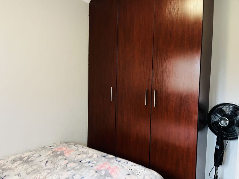 A bedroom featuring a large, dark wood-finish built-in wardrobe providing ample storage space.