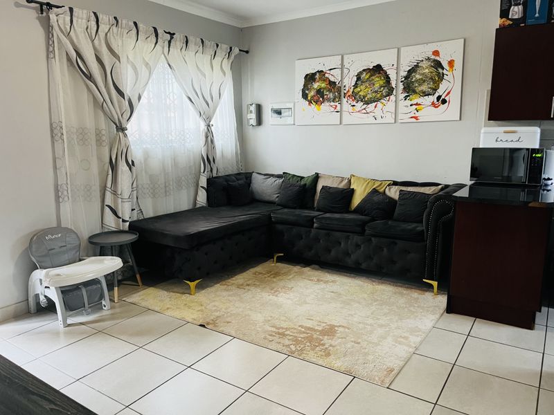 An open-plan living area featuring tiled flooring and neutral wall finishes, seamlessly connecting to the adjacent kitchen space.