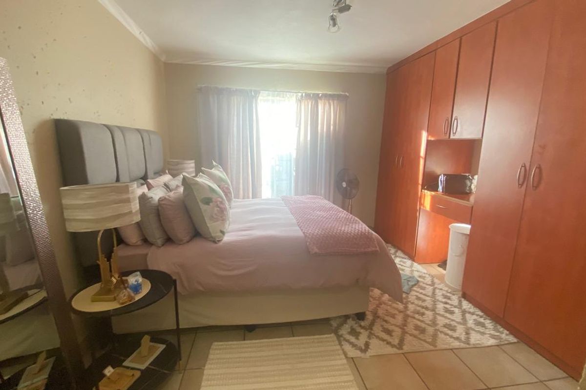 A bedroom featuring built-in wooden cabinetry with an integrated desk area and tiled flooring, offering functional storage and a neutral layout.