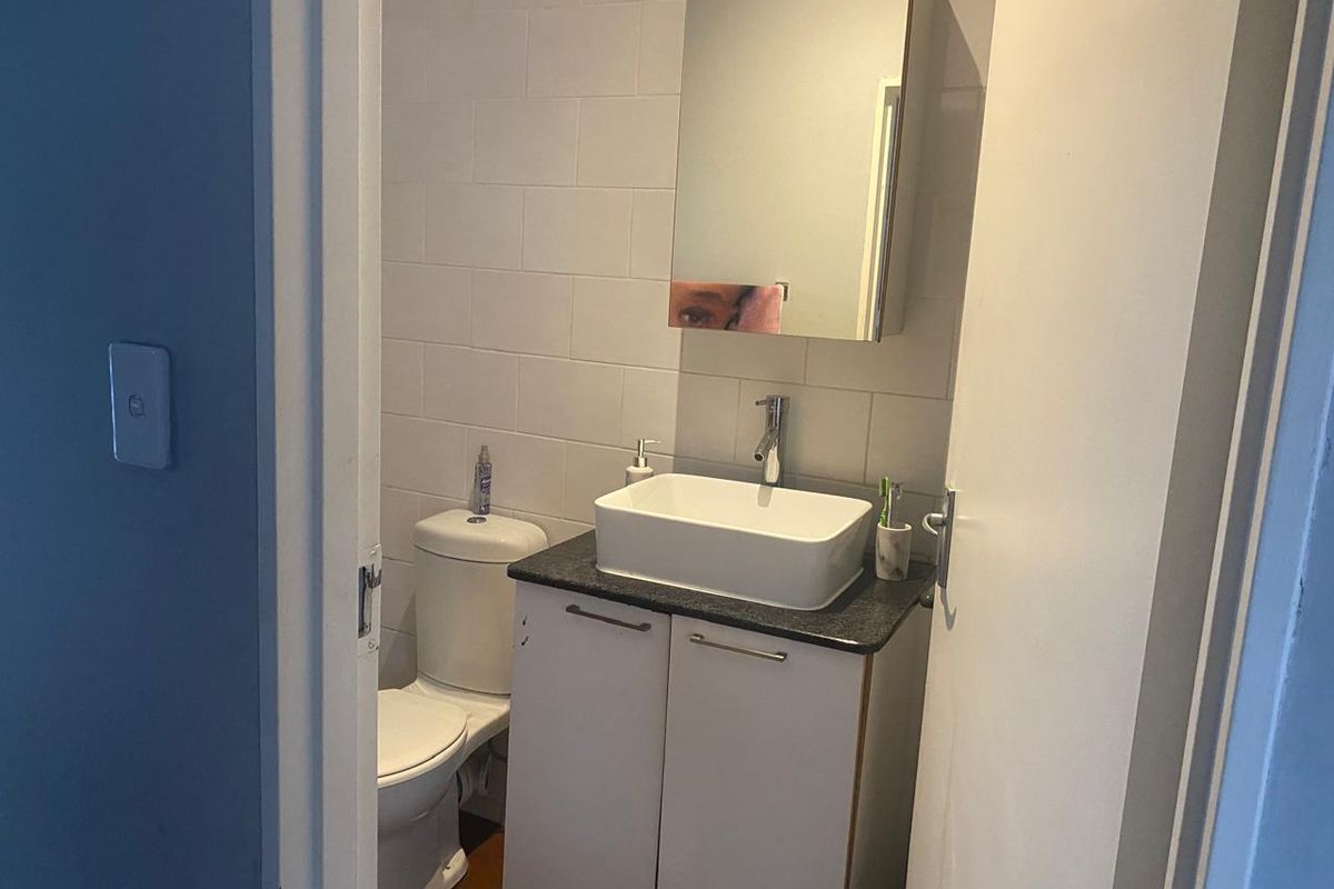Compact bathroom featuring a modern vessel sink vanity, wall-mounted mirrored cabinet, and a standard toilet.
